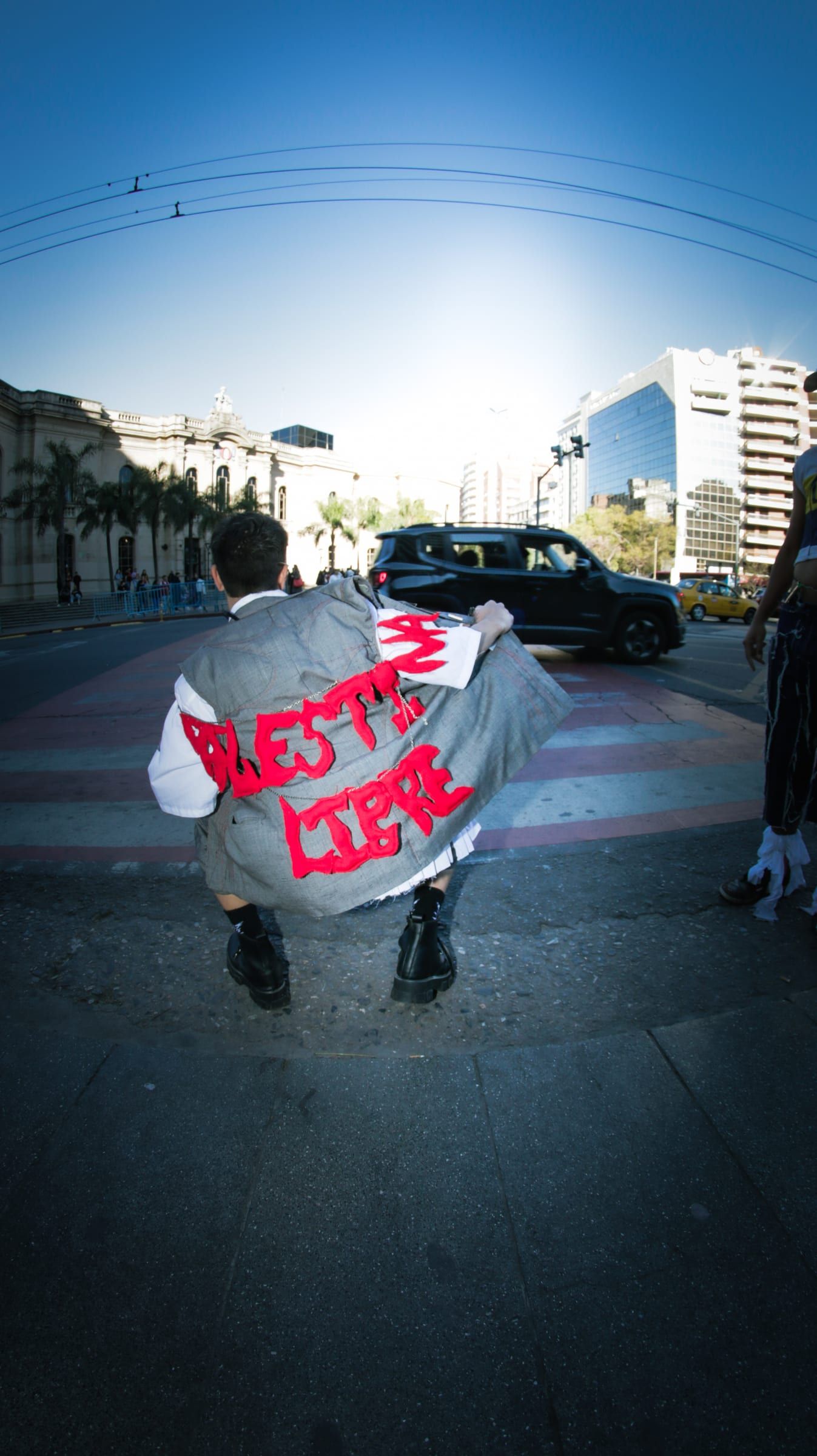 The back of a jacket with red letters painted by hand, in the middle of the street.