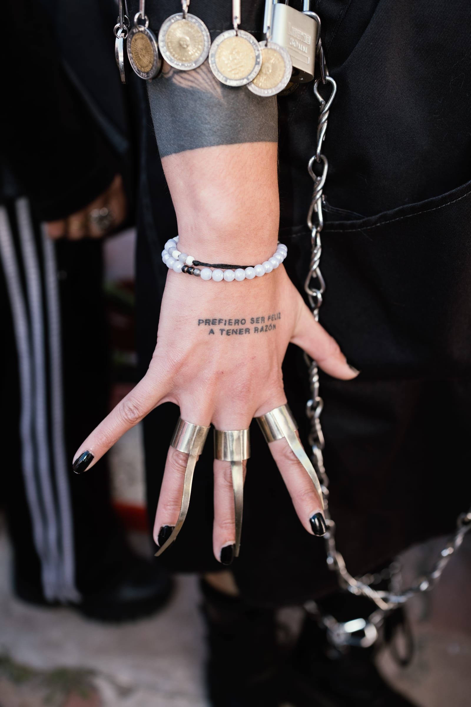 A hand with long silver rings and a chain hanging from the wrist.