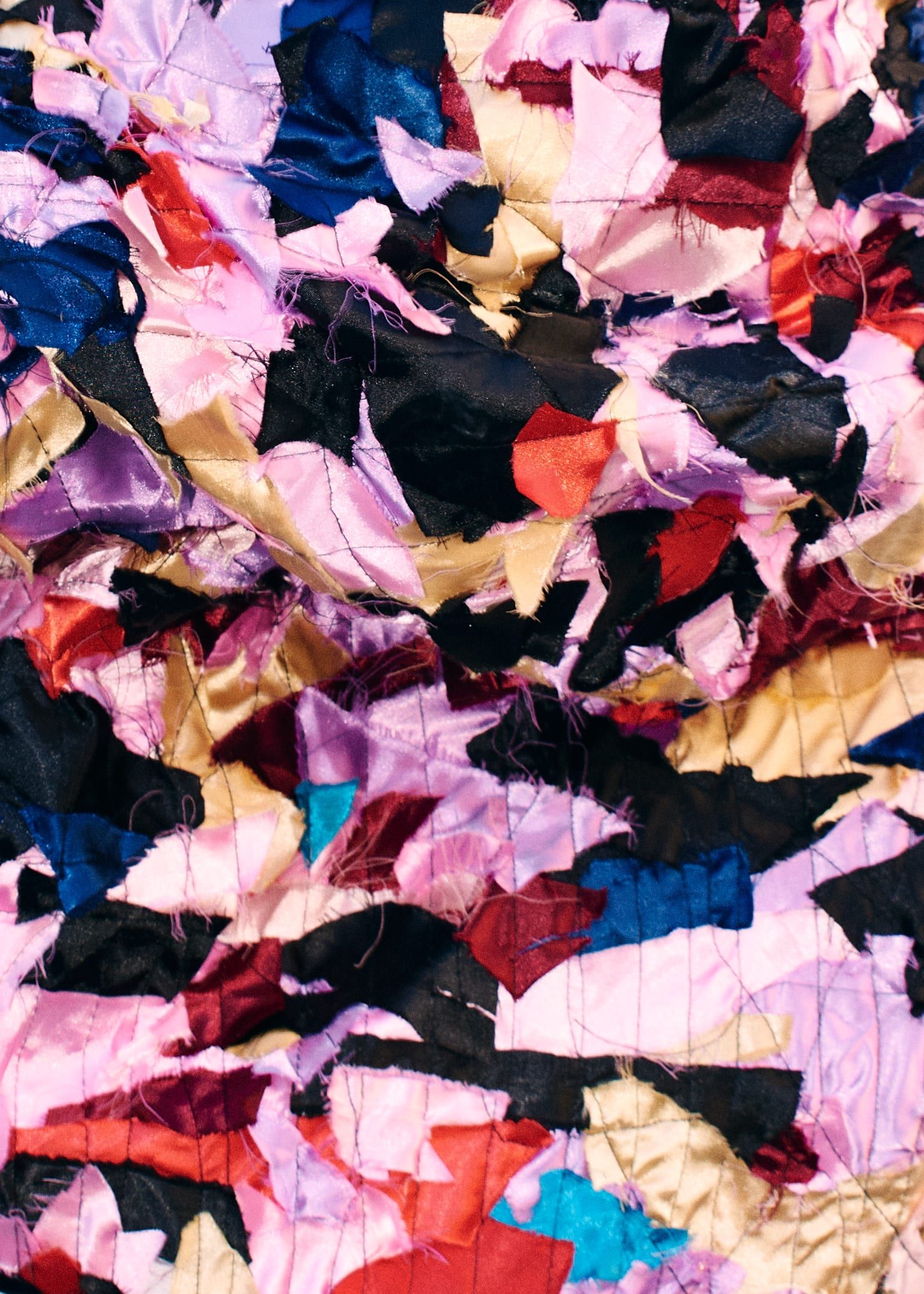 Texture of coloured fabric scraps sewn one over another.
