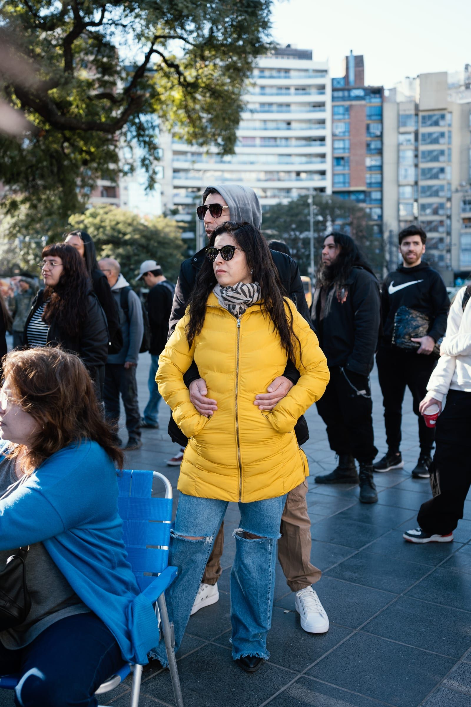 Onlookers standing and sitting in folding chairs watch the show; in the centre, a yellow jacket.