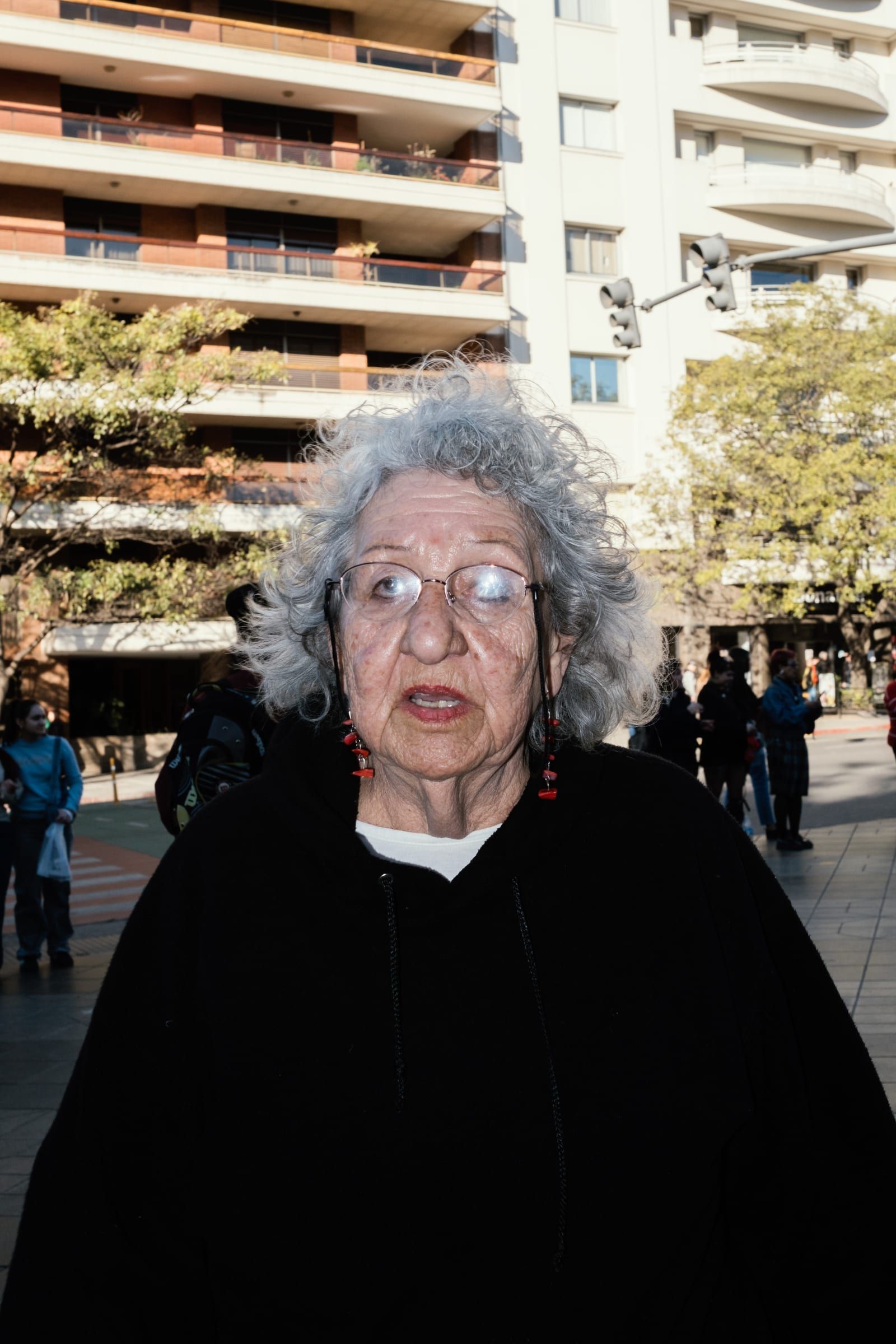 Portrait of an older woman with grey hair looking at the camera from the crowd.