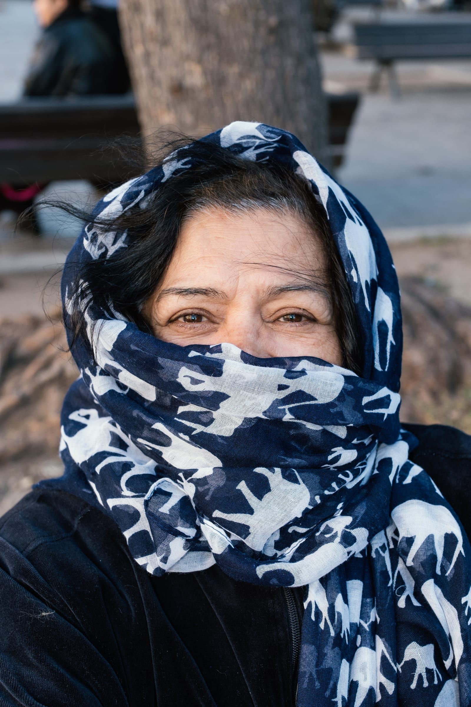 A woman with a patterned scarf covering her mouth watches the show.